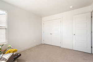 Unfurnished bedroom with light colored carpet and a closet
