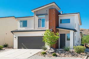 View of front of property with concrete driveway, a garage, and stucco siding