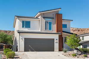 View of front of home featuring a garage, driveway, a mountain view, and stucco siding