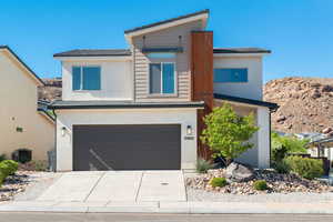 View of front of property featuring driveway, a garage, and stucco siding