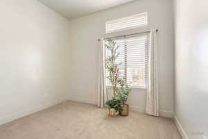Empty room featuring light colored carpet and baseboards