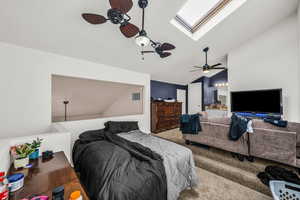 Bedroom with a skylight, lofted ceiling, carpet floors, ensuite bath, and ceiling fan