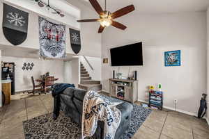 Living area featuring light tile patterned floors, ceiling fan, and a high ceiling