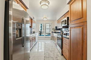 Kitchen featuring stainless steel appliances, wood finish cabinetry, and dark stone countertops