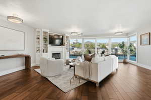 Living room featuring dark wood-style flooring and a glass covered fireplace
