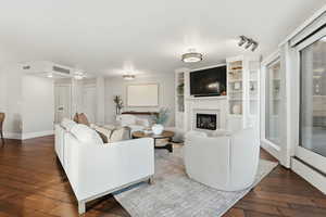 Living area with a glass covered fireplace and dark wood finished floors