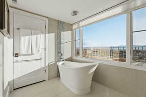 Full bathroom featuring a soaking tub, light tile patterned floors, and tile walls