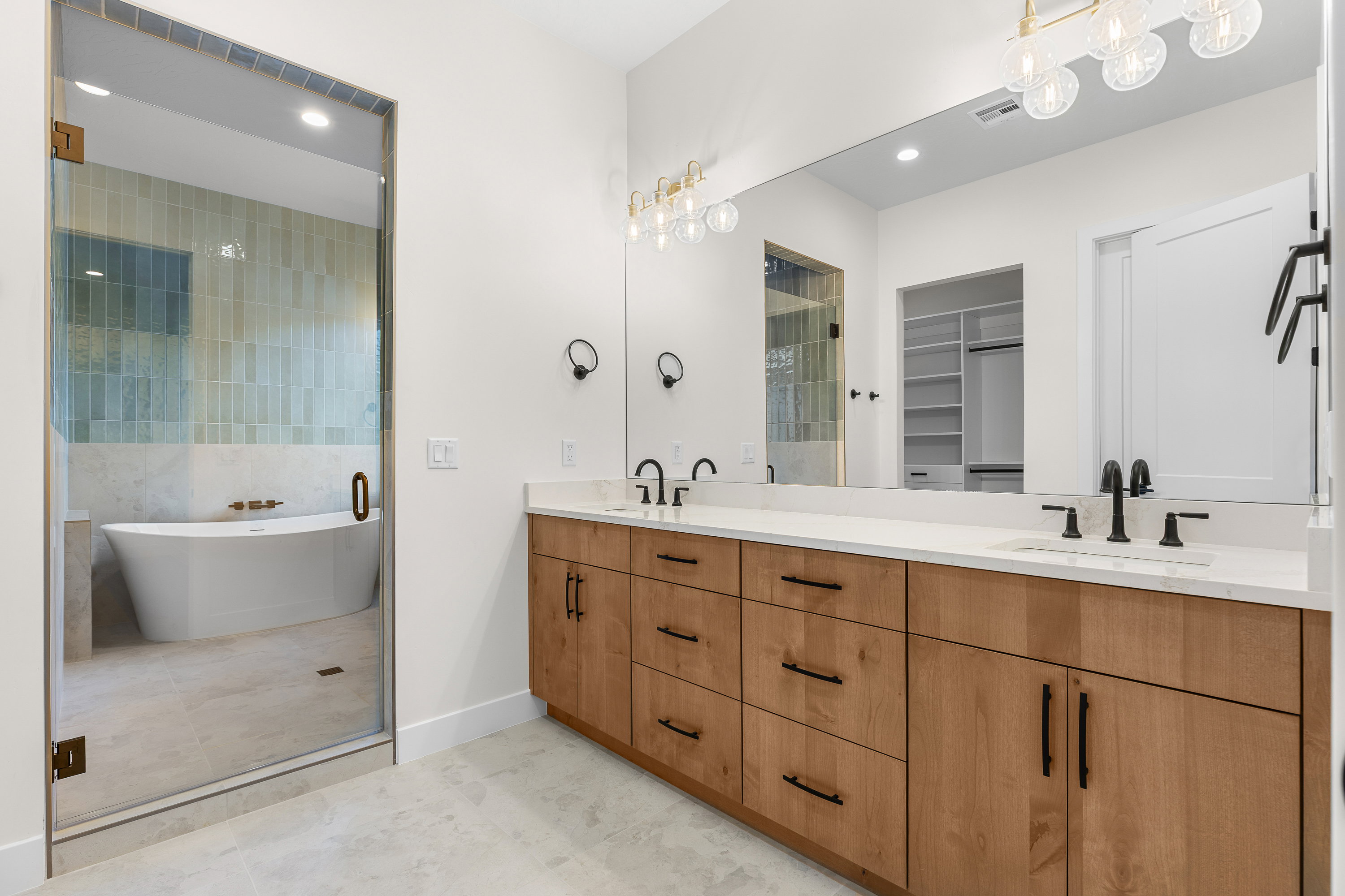 Full bath with double vanity, a freestanding tub, a spacious closet, recessed lighting, and light tile patterned floors