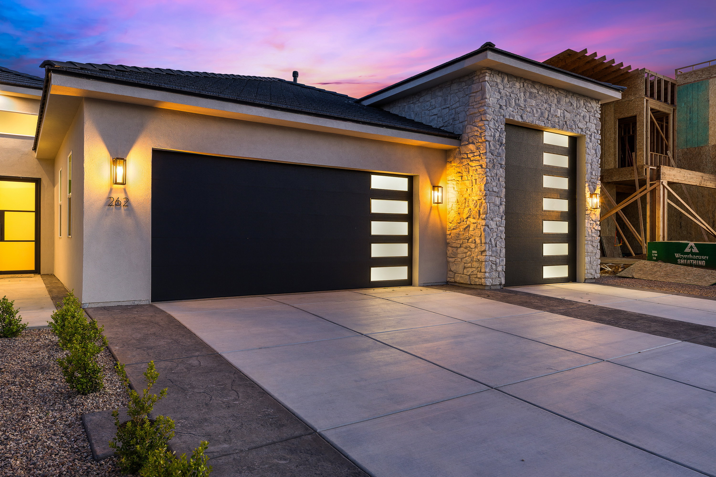 Contemporary home featuring stone siding, an attached garage, concrete driveway, and stucco siding