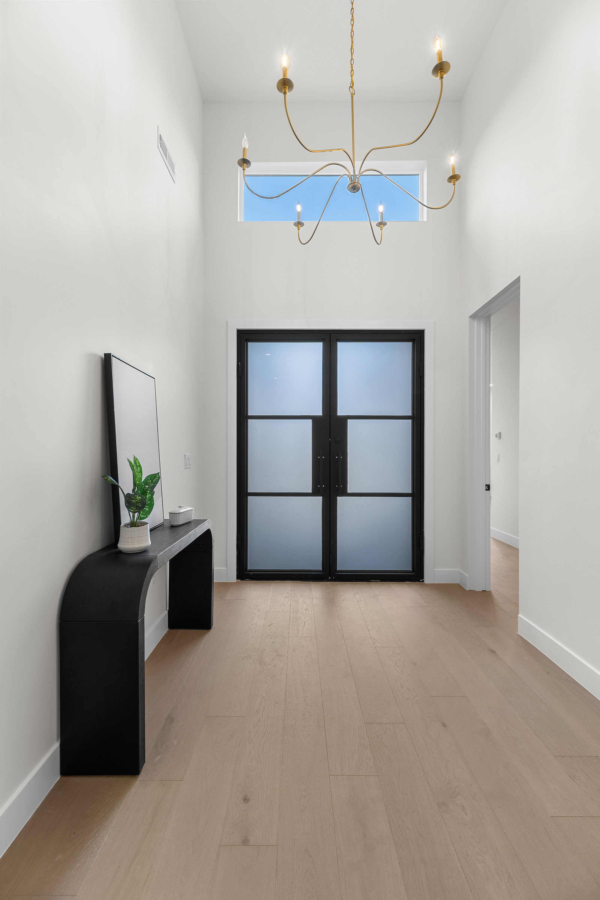 Foyer featuring a high ceiling, a chandelier, french doors, light wood-style floors, and healthy amount of natural light