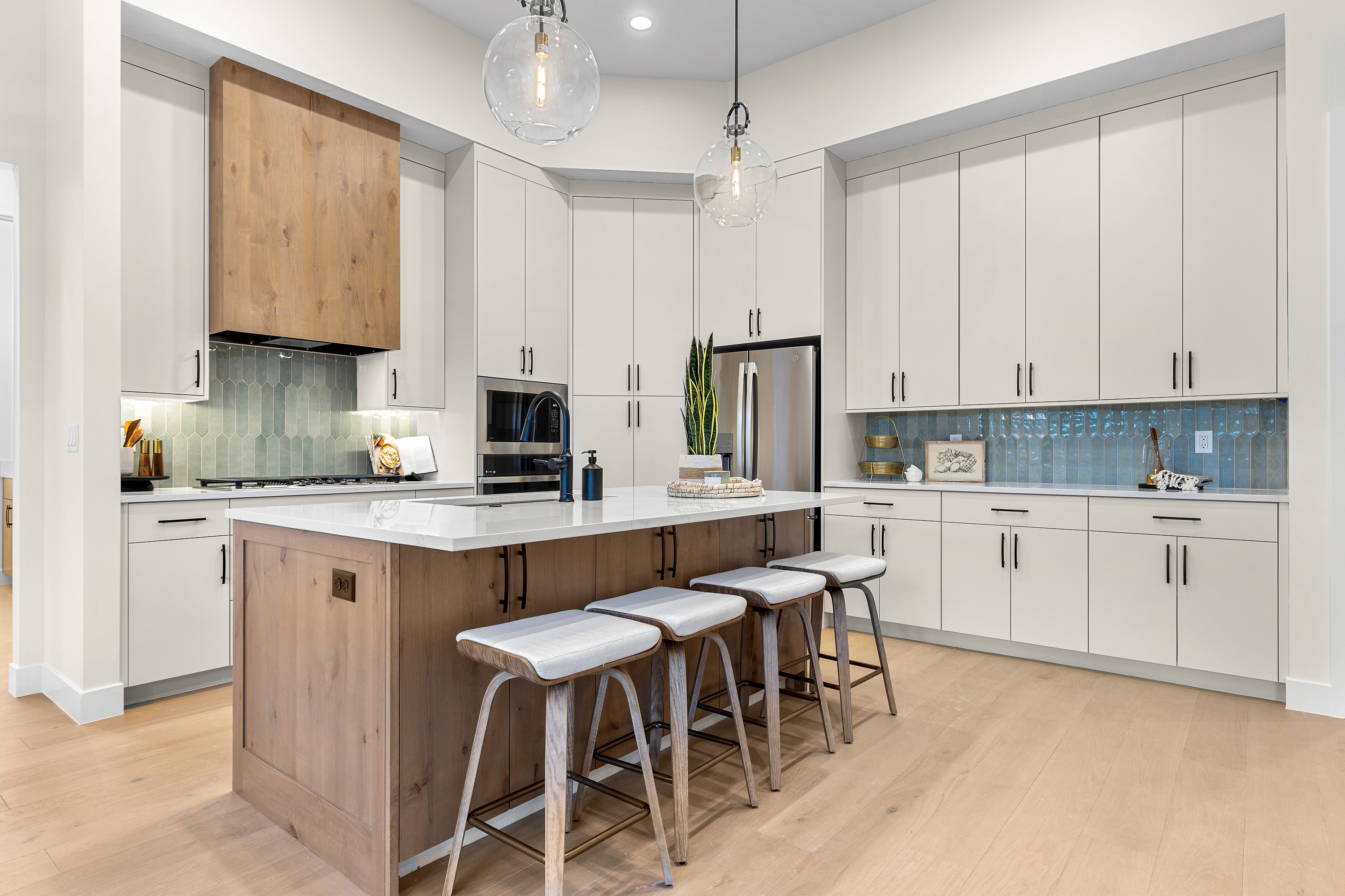Kitchen with two tone cabinetry, a breakfast bar, light wood-style floors, decorative backsplash, and a center island with sink
