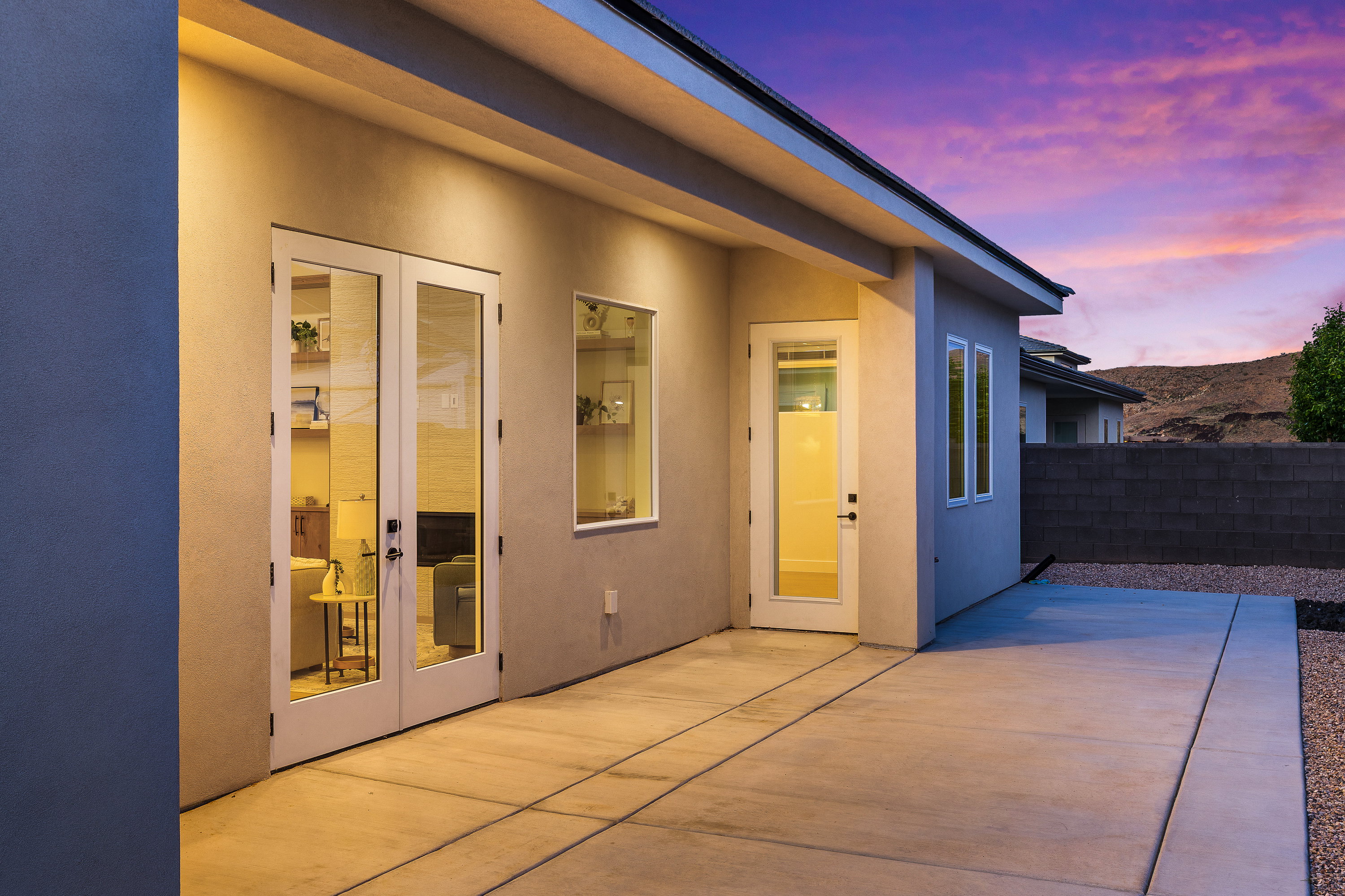 Exterior entry at dusk featuring french doors, a patio, and stucco siding