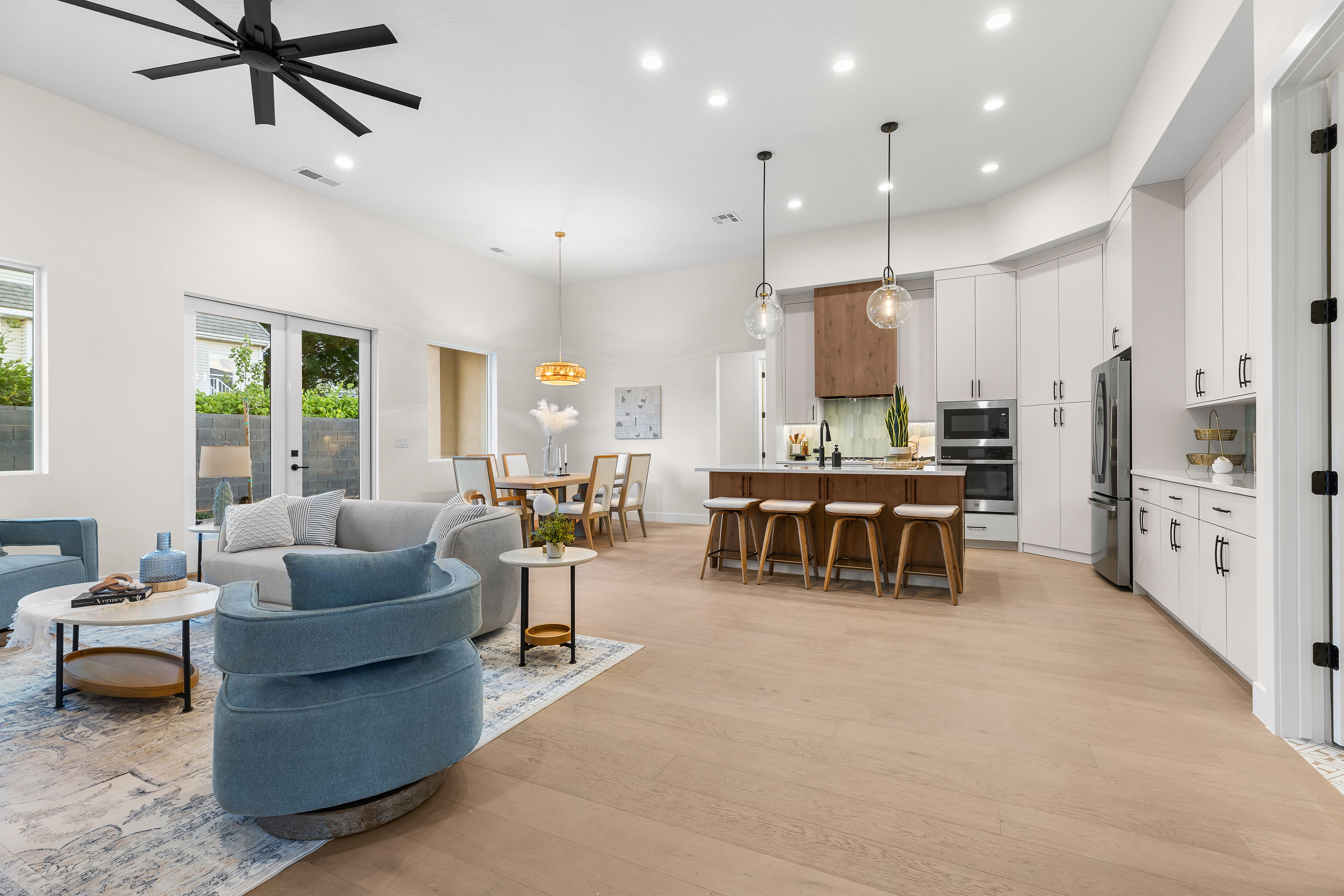 Living room with light wood finished floors, recessed lighting, french doors, a high ceiling, and ceiling fan