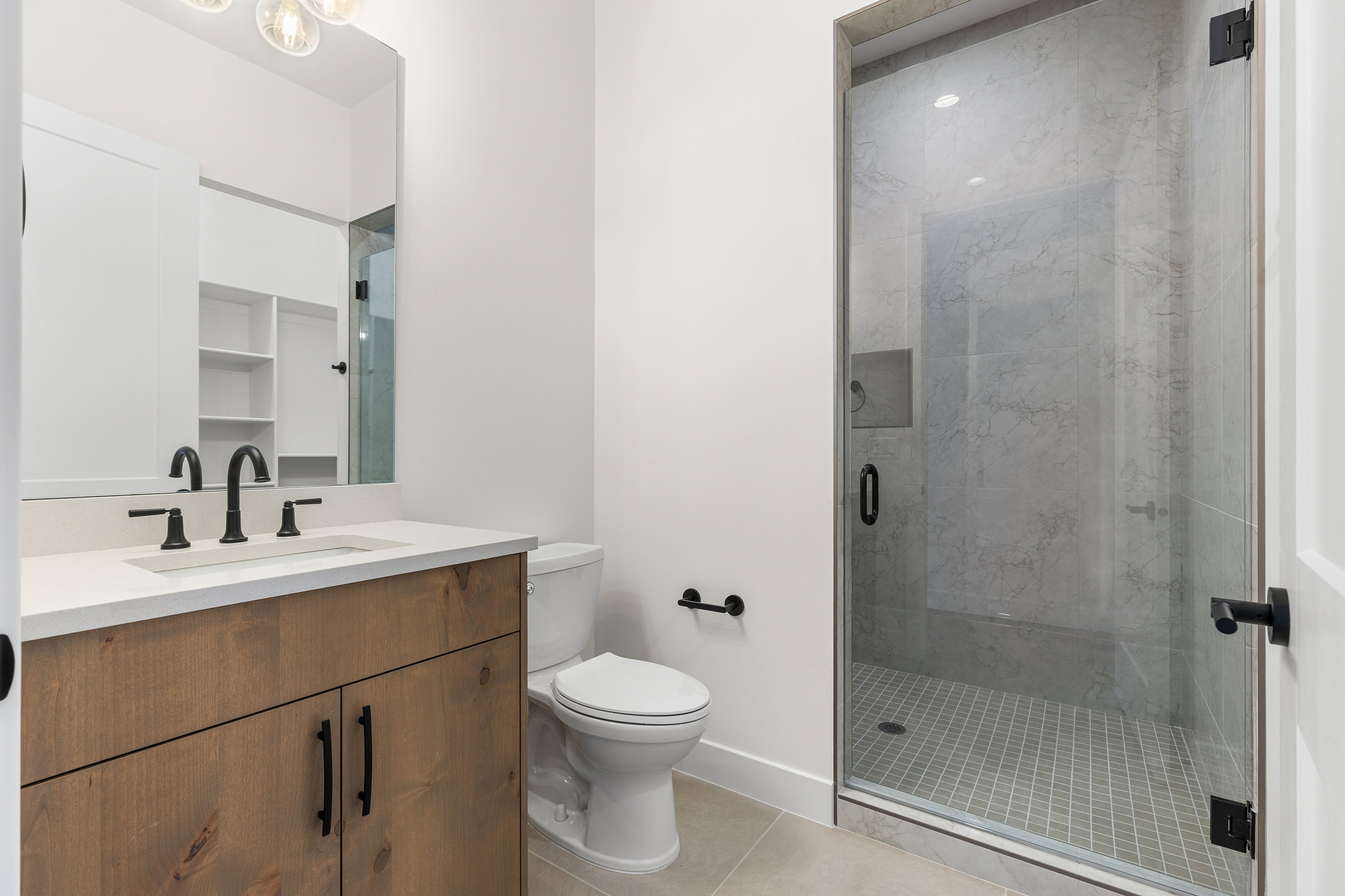Bathroom featuring vanity, a marble finish shower, and light tile patterned floors