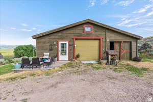 Rear view of property with a patio area, an outbuilding, a detached garage, and an outdoor living space
