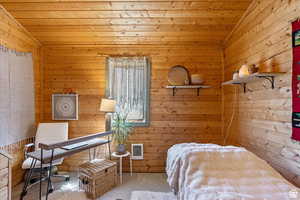 Carpeted bedroom featuring wooden walls, a vaulted wooden ceiling, heating unit, and an office area