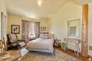 Bedroom featuring wood finished floors, vaulted ceiling, and heating unit