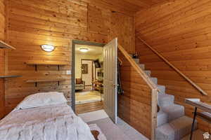 Carpeted bedroom featuring wooden walls