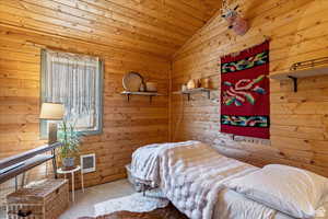 Bedroom featuring carpet, vaulted ceiling, wooden walls, and heating unit