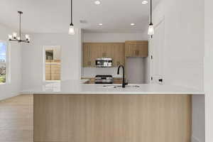 Kitchen with stainless steel appliances, light stone counters, tasteful backsplash, hanging lights, and a peninsula