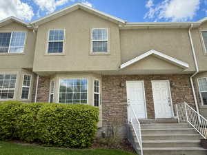 View of front facade featuring stucco siding and stone siding