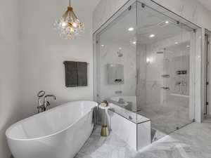 Full bath with a freestanding tub, light marble finish floors, hanging lights, and a marble finish shower