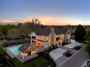 Rear view of house with a fenced backyard, stone siding, a patio, and a balcony