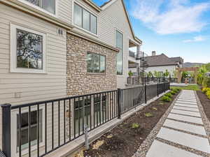 View of side of home featuring stone siding, a balcony, and a patio area