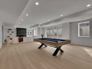 Rec room featuring light wood finished floors, pool table, a fireplace, recessed lighting, and built in shelves