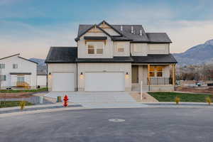 Modern farmhouse with a porch, board and batten siding, concrete driveway, roof with shingles, and a mountain view
