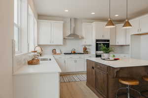 Two tone kitchen with dual tone cabinetry, a kitchen breakfast bar, backsplash, a kitchen island, and decorative light fixtures