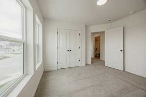 Unfurnished bedroom featuring light colored carpet and a closet