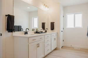 Bathroom with double vanity and light wood-type flooring