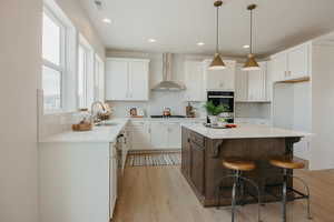 Kitchen featuring a kitchen breakfast bar, a center island, dual tone cabinets, light wood-type flooring, and light stone counters