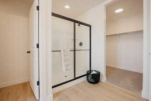 Bathroom featuring a walk in closet, recessed lighting, a stall shower, and light wood-style floors