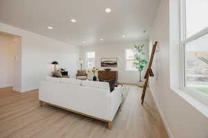 Living area with light wood-style floors, recessed lighting, and a fireplace