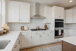 Kitchen featuring stainless steel appliances, backsplash, light wood finished floors, recessed lighting, and light stone countertops