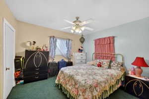 Bedroom with dark colored carpet and ceiling fan