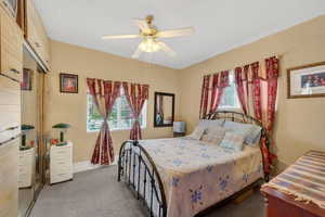 Bedroom with dark colored carpet, a ceiling fan, and a textured ceiling