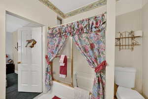 Bathroom featuring toilet and shower / bath combination with glass door