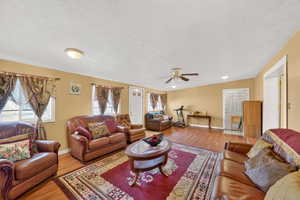 Living area featuring wood finished floors, a ceiling fan, and a textured ceiling
