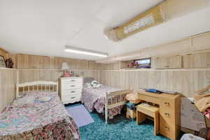 Bedroom featuring wooden walls and dark carpet
