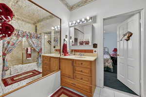 Full bathroom with vanity, connected bathroom, backsplash, and light tile patterned floors