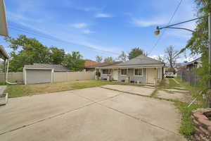 Rear view of house with a fenced backyard, roof with shingles, and an outbuilding