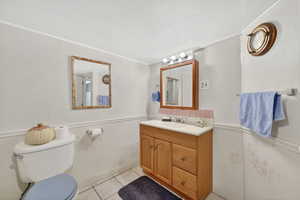 Bathroom with a wainscoted wall, tile walls, vanity, and light tile patterned floors