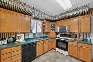Kitchen with electric range, open shelves, black dishwasher, wallpapered walls, and stainless steel microwave