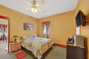 Carpeted bedroom with a ceiling fan