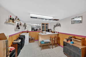 Bar area with wainscoting, washer / dryer, a textured wall, light countertops, and wooden walls