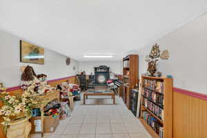 Interior space featuring a wainscoted wall, wooden walls, light tile patterned floors, and a textured wall