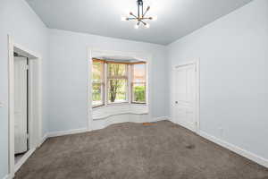Unfurnished bedroom featuring dark colored carpet and suspended lighting